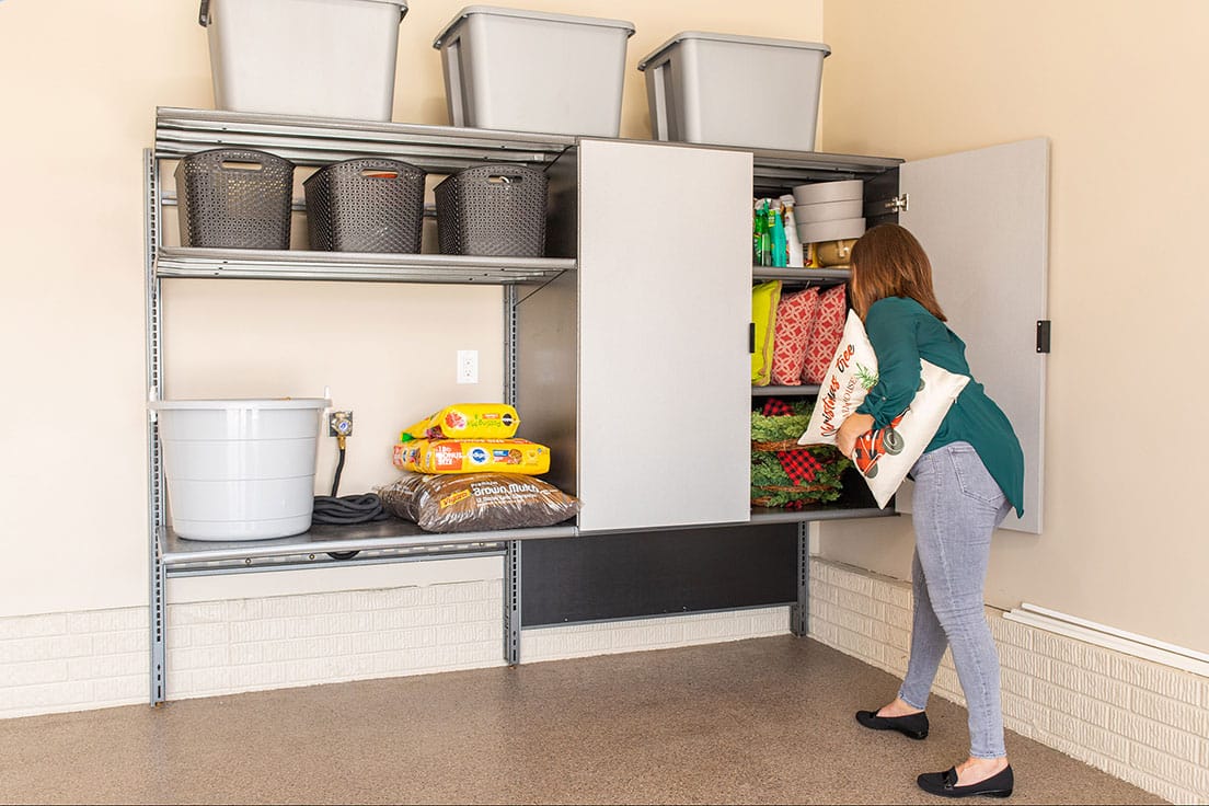 A woman storing items in a garage cabinet