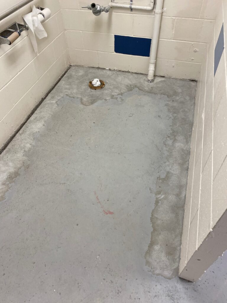 Stained concrete in a school bathroom before a concrete coating