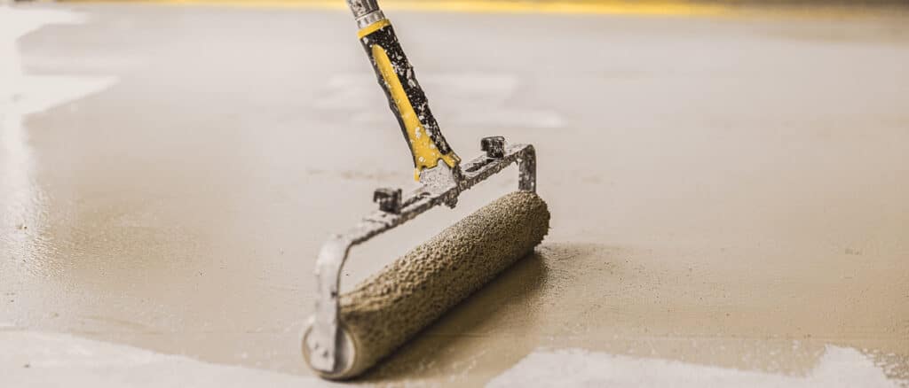 Roller putting on a garage floor coating