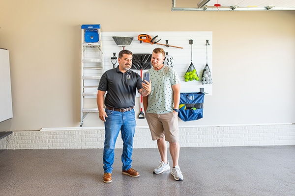 Two men looking at a phone with wall storage behind them