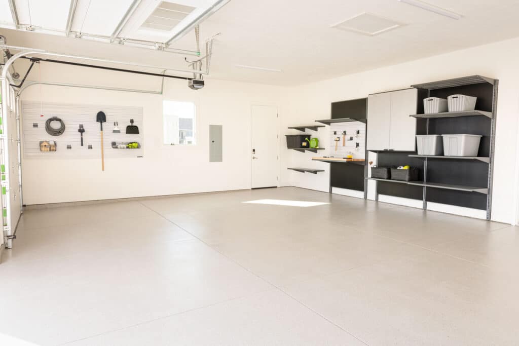 Garage Makeover with a new garage floor coating, slatwall with hooks, shelves, and a workbench